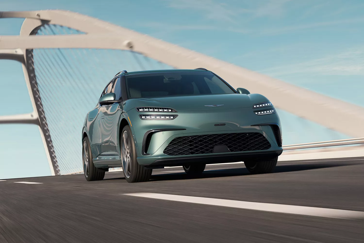 A sleek, modern Genesis electric car driving on a bridge with a clear sky in the background.