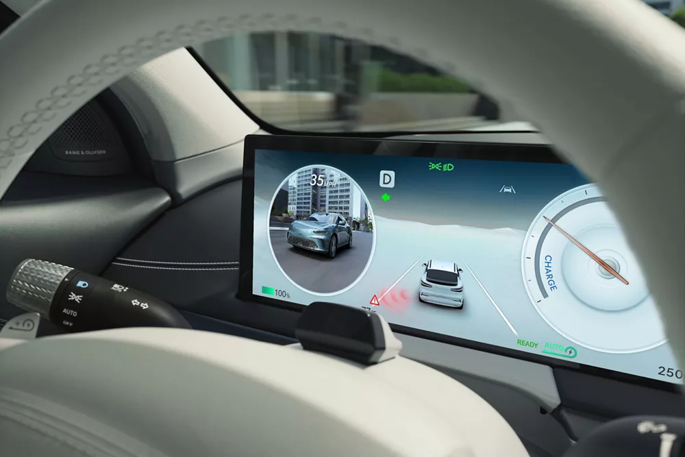 Digital dashboard showing navigation, speed, and battery charge information behind the steering wheel.
