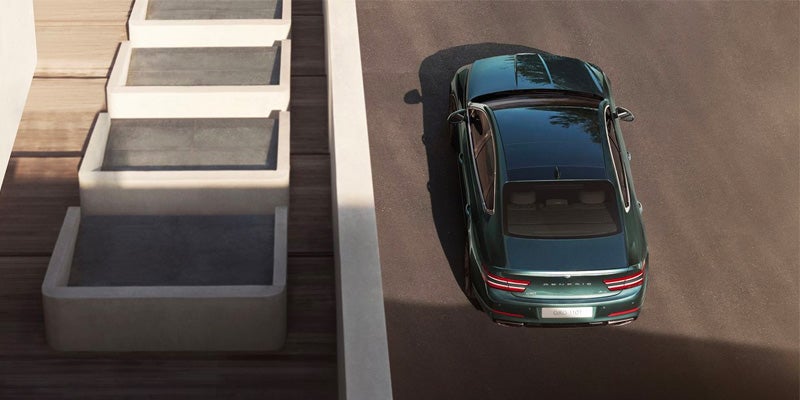 An overhead view of a dark green car parked on the pavement.