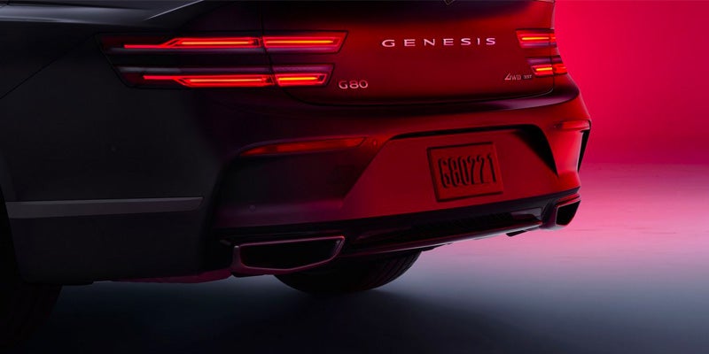 Rear view of a Genesis G80 car with glowing taillights against a gradient background.