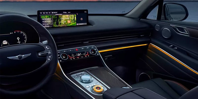 Interior view of a 2026 Genesis GV80, featuring a steering wheel, dashboard display, and central console with controls. The design is modern with ambient lighting accents.