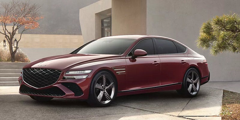 A red Genesis G80 parked outside a modern building.