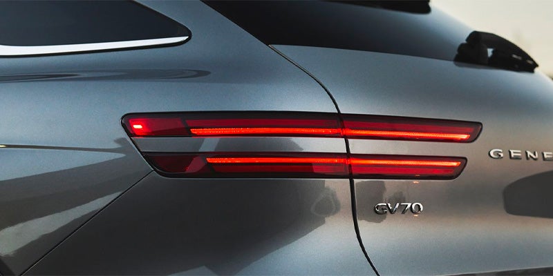 Close-up of the 2026 Genesis GV70 rear LED taillights and model badging on a sleek gray luxury SUV.