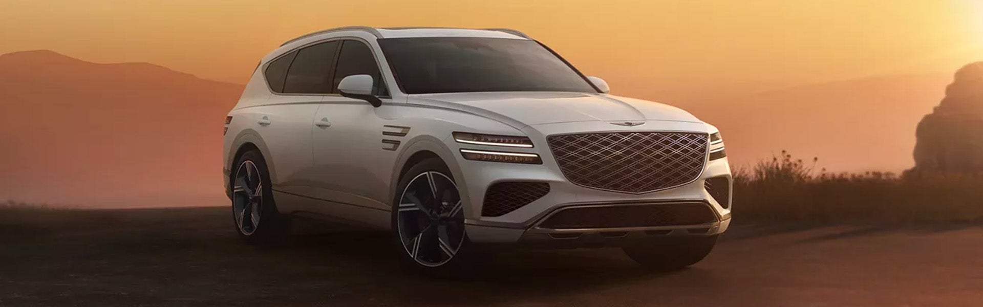 A white SUV with headlights on, at sunrise or sunset.