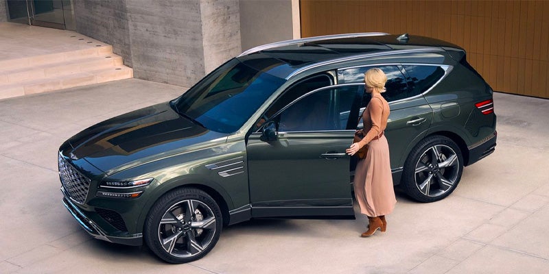 A woman opening the driver's side door of a green SUV