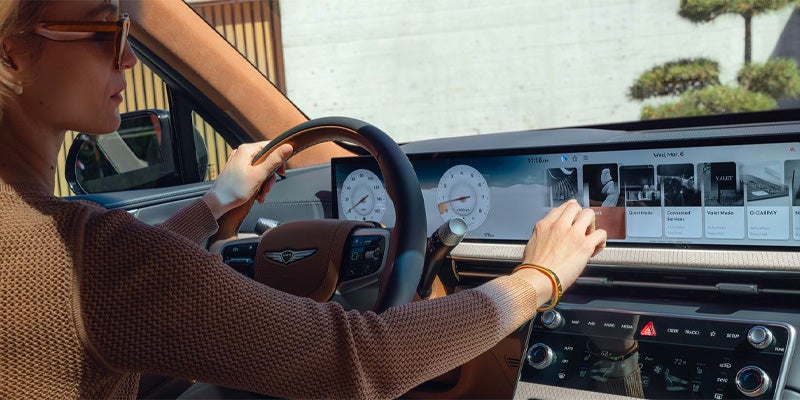 A person's hands on the steering wheel, using the car's screen