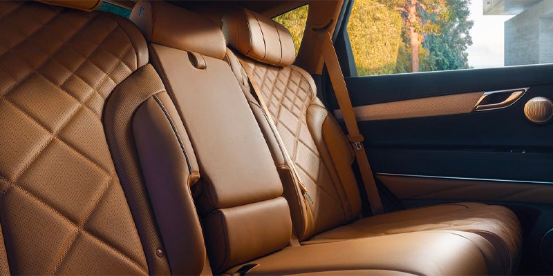 The tan leather, diamond-stitched back seats of a car